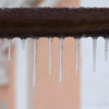 What to Do About Frozen Pipes frozen icicles hanging off of a dirty pipe in the midst of winter.